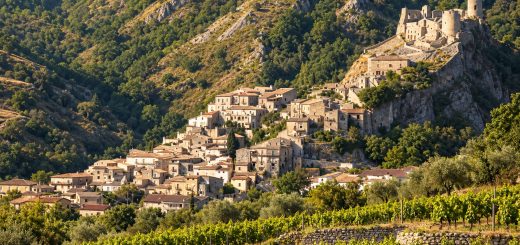 Vigneti terrazzati della Savuto DOC davanti a un borgo arroccato della Calabria